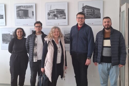 5 persons in front of pictures of buildings