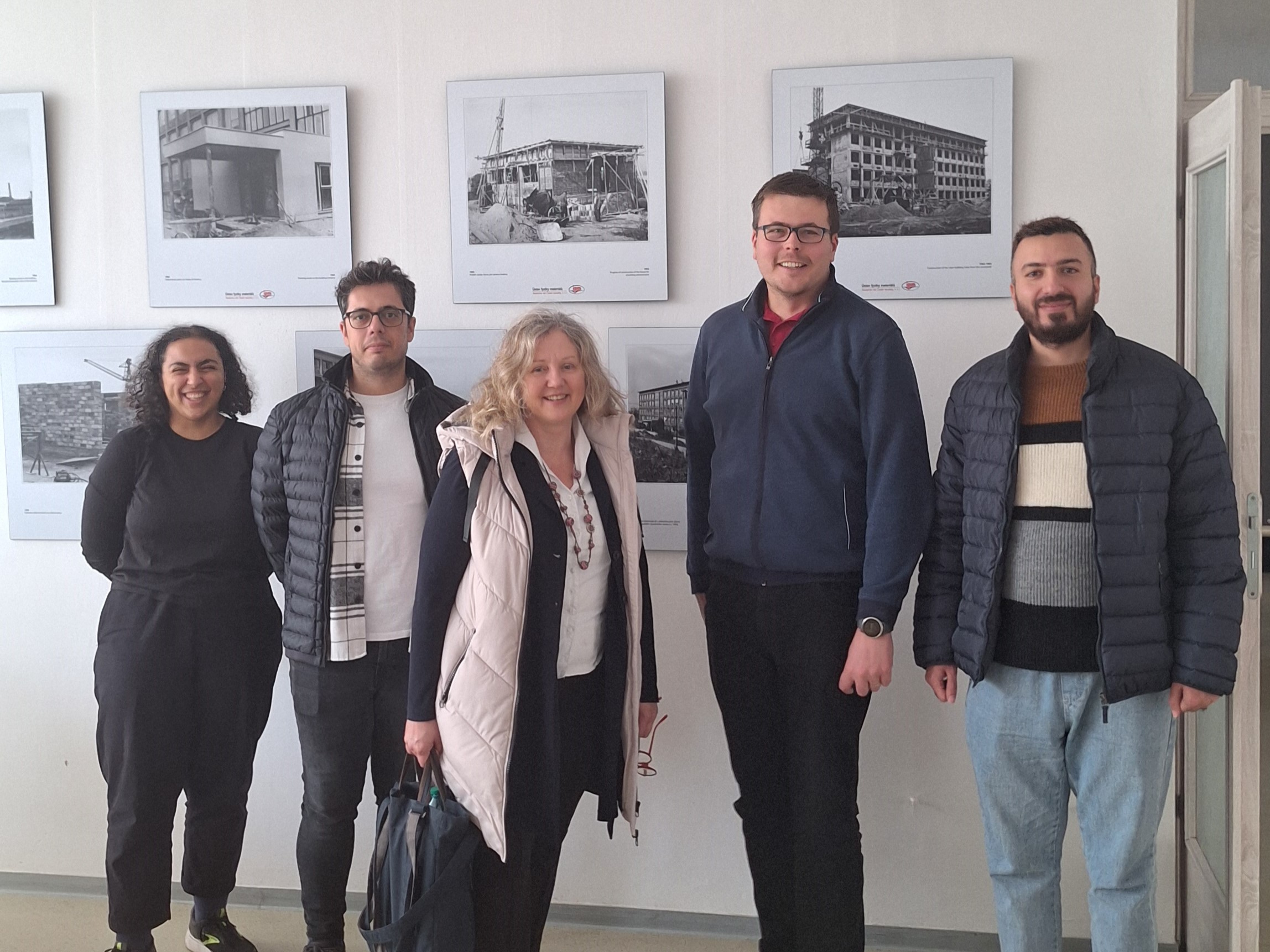 5 persons in front of pictures of buildings