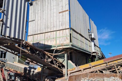 scrap inside a trough in front of a conveyor belt