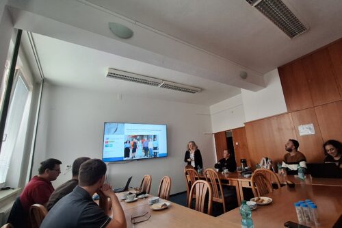 a monitor and several people in a conference room