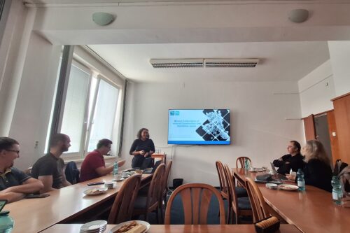 a monitor and several people in a conference room