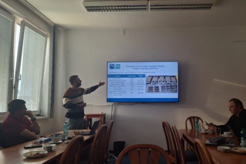 a monitor and several people in a conference room