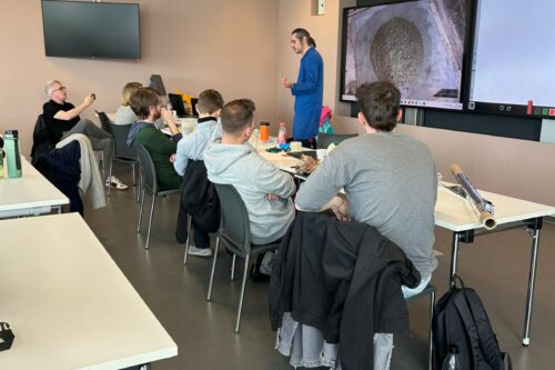 a person presenting in a room in front of several sitting persons