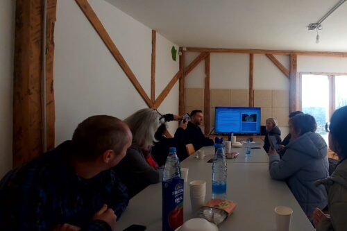 people sitting in a room around a chair looking at a presentation