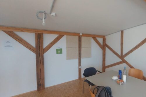 inside of a room with white walls, hempstatic panels, wooden elements, and a table with chairs