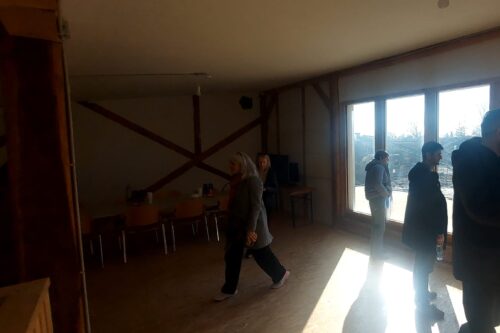 people standing inside a room with big windows and hempstatic panels on the wall